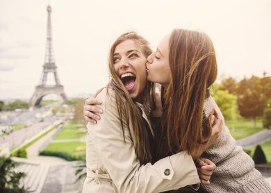 Frau küsst ihre glückliche Partnerin vor dem Eiffelturm in Paris.  | © Gettyimages.com/filadendron