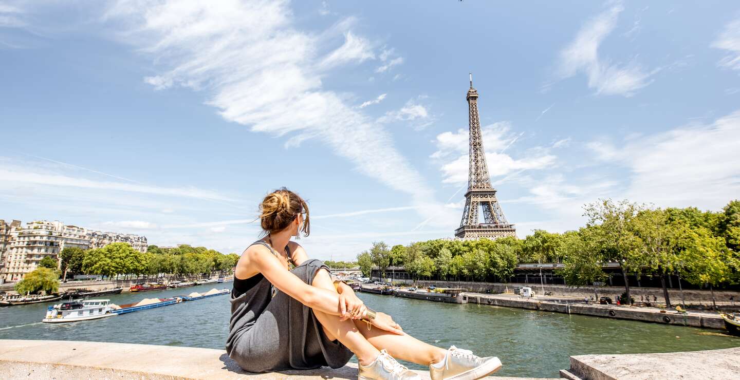 Junge stilvolle Frau mit herrlichem Blick auf den Eiffelturm auf der Brücke in Paris | © Gettyimages.com/RossHelen