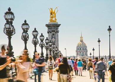Fußgänger laufen auf der Pont Alexandre III in Paris an einem sonnigen Sommertag. | © Gettyimages.com/espiegle