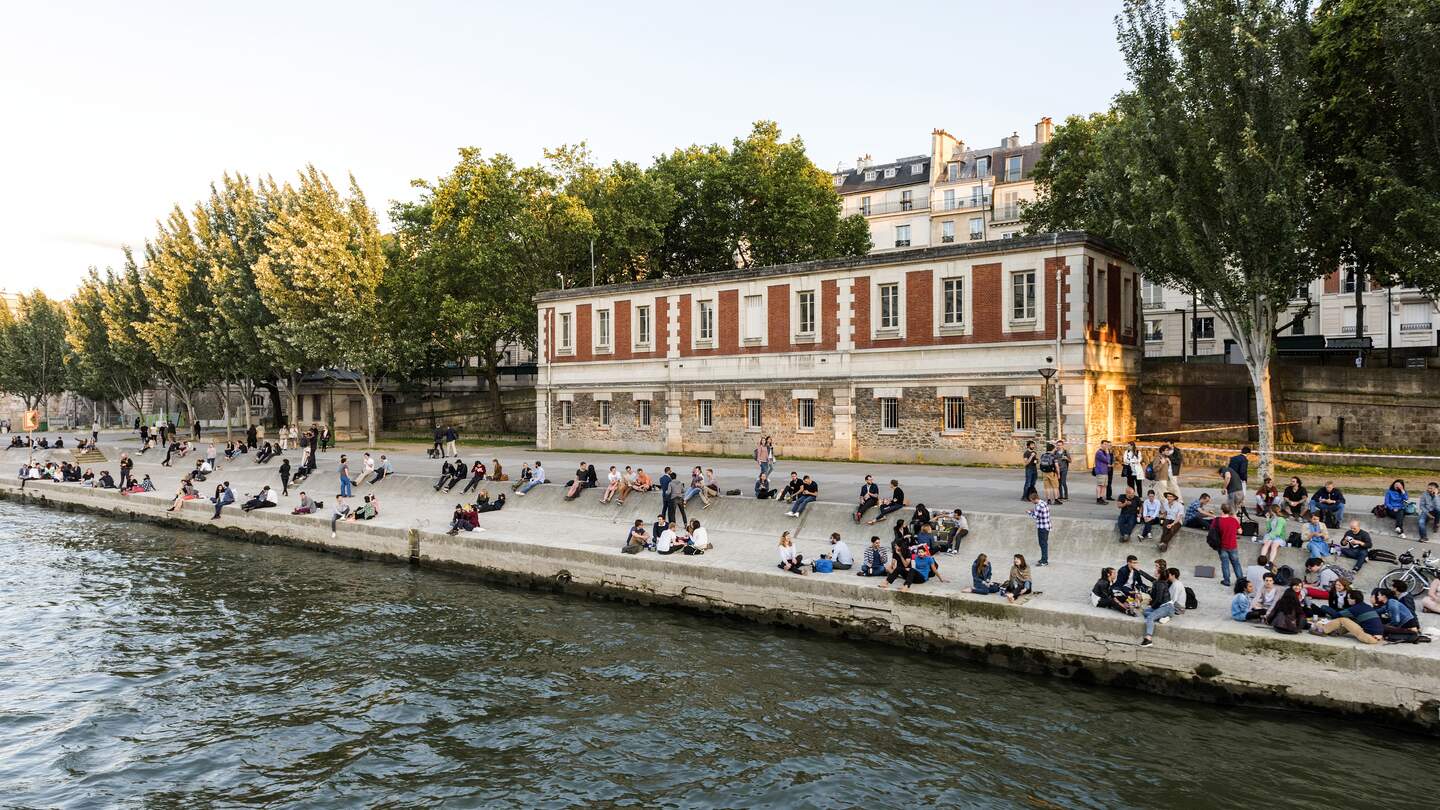 Menschen sitzen am Ufer der Seine in Paris. | © Gettyimages.com/omersukrugoksu