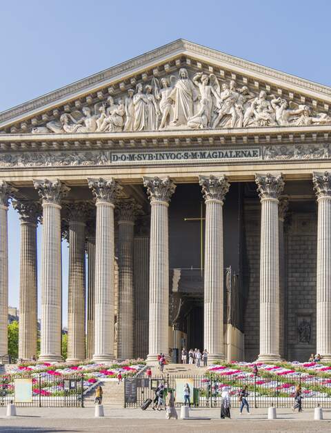 Passanten neben „L'église de la Madeleine“ (Kirche La Madeleine) in Paris, Frankreich. Es liegt am Ende der Rue Royale und wurde 1928 fertiggestellt. Es ist beruehmt fuer seine Architektur in Form eines roemischen Tempels. | © Gettyimages.com/Mauro_Repossini