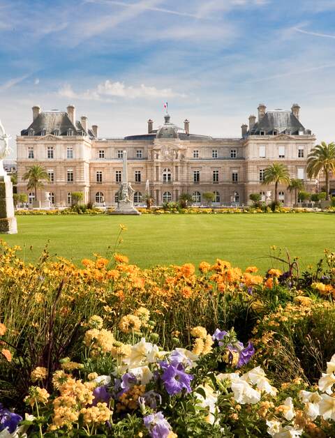 Jardin du Luxembourg mit dem Palast, Statue,Blumen sind vorne und blauer Himmel dahinter. | © gettyimages.com/vkovalcik