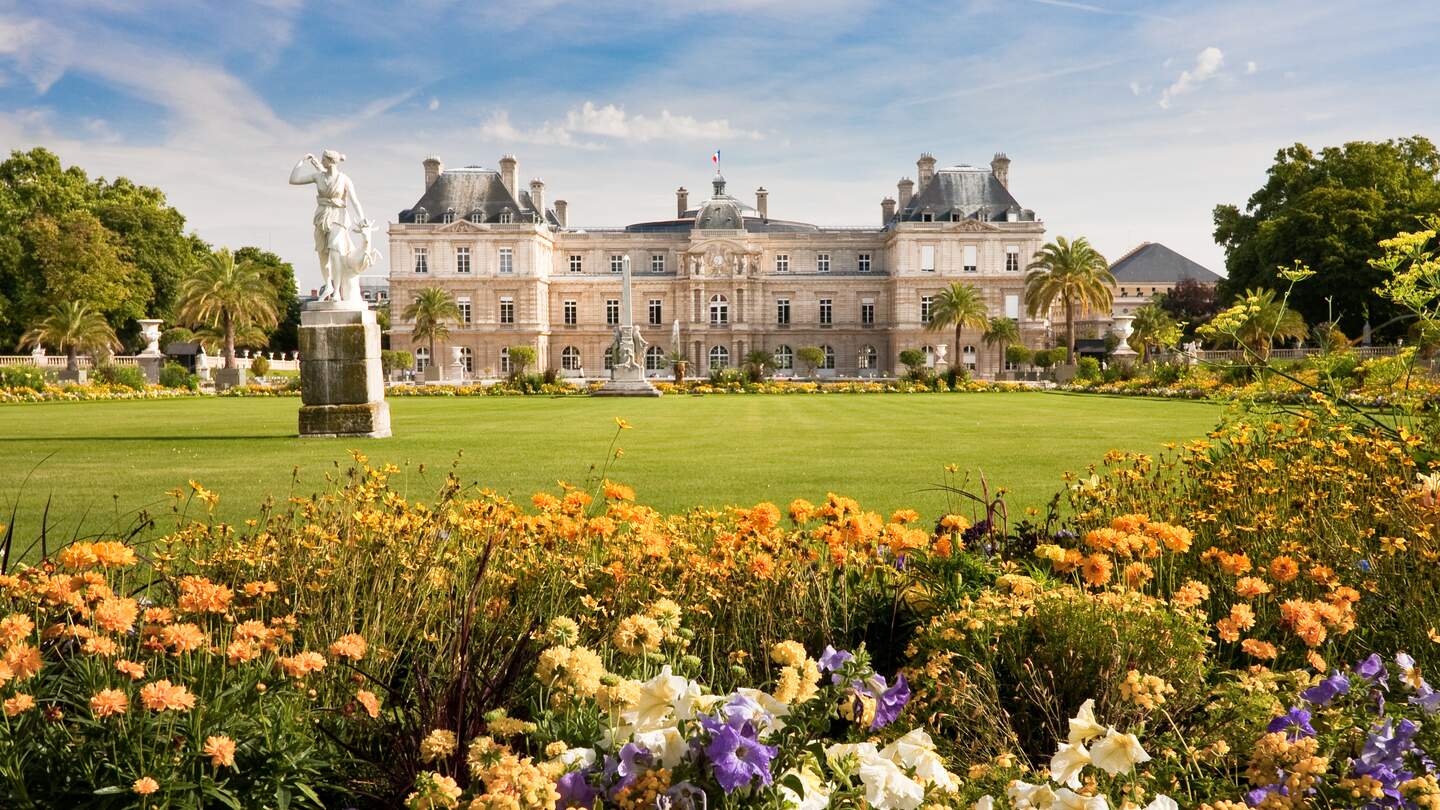 Jardin du Luxembourg mit dem Palast, Statue,Blumen sind vorne und blauer Himmel dahinter. | © gettyimages.com/vkovalcik