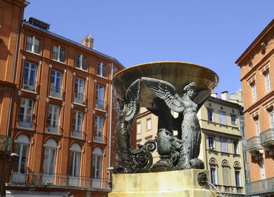 Blick auf französische Backsteingebäude und Brunnen in Toulouse, Place de la Trinite | © Gettyimages.com/yvon52 