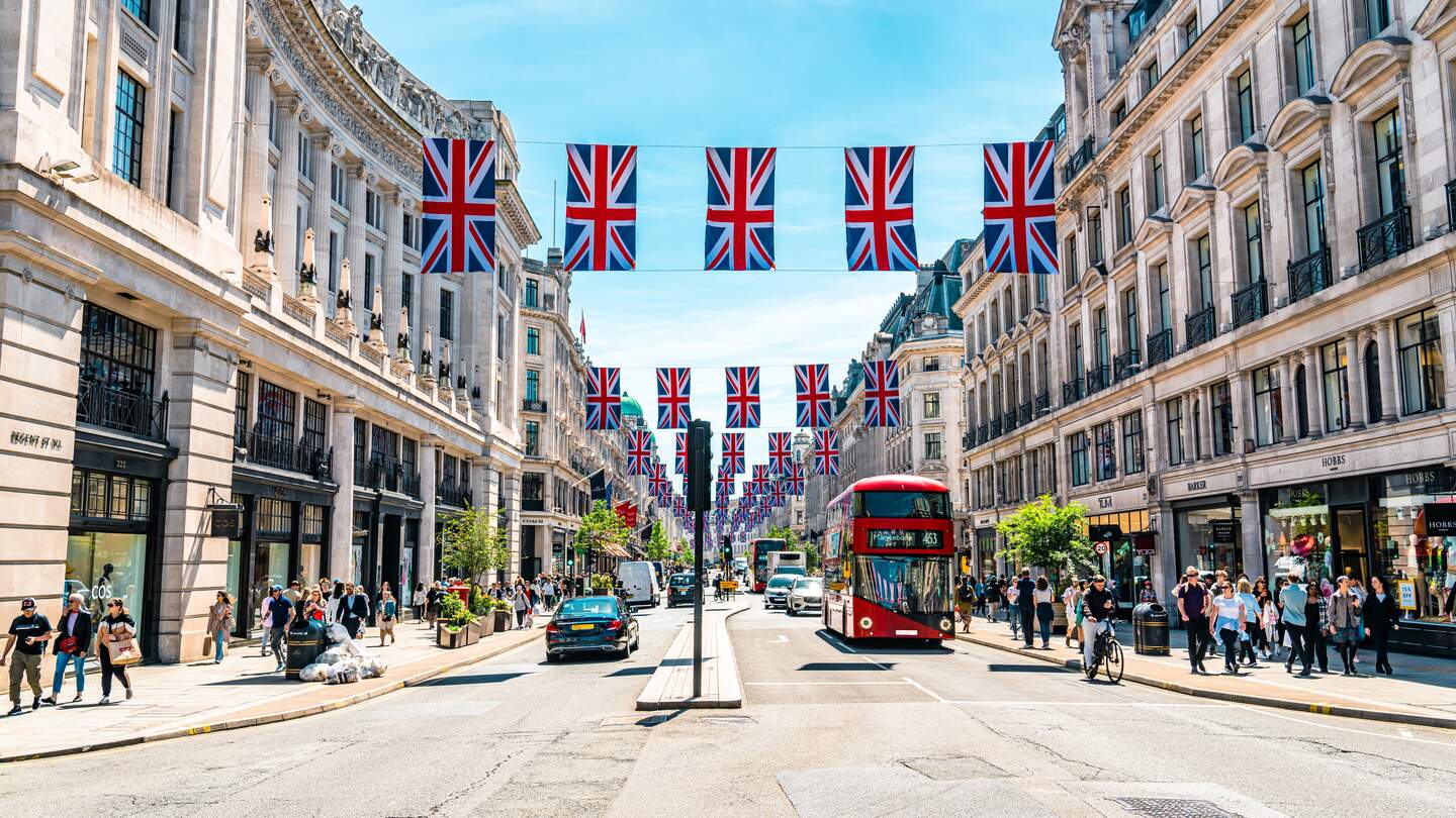 Blick auf eine Straße in London mit einem rotem Doppeldecker und englischen Flaggen | © Gettyimages.com/CHUNYIP WONG