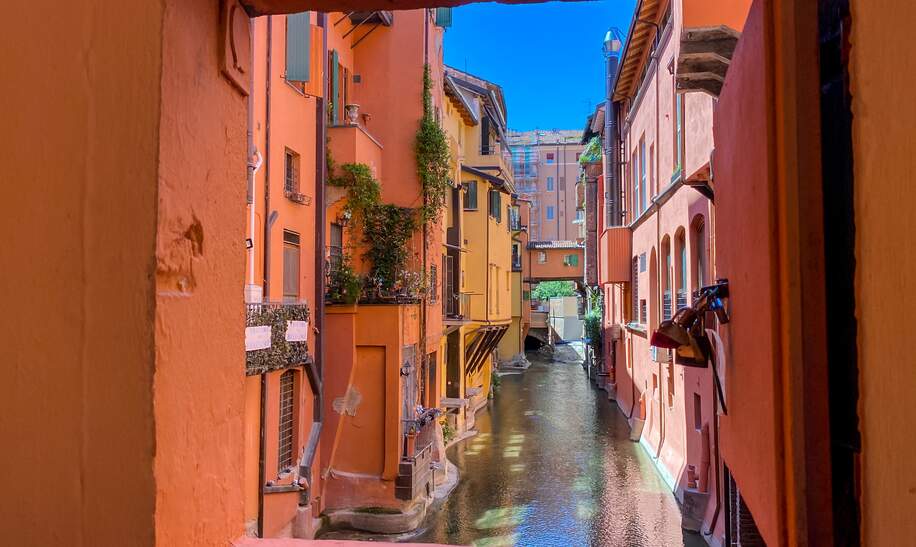 Blick auf einen kleinen Kanal in Bologna durch ein rot umrahmtes Fenster | © Gettyimages.com/todamo