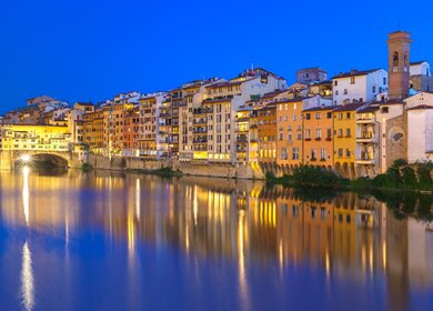 Alte Haeuser und Turm am Ufer des Flusses Arno und Ponte Vecchio bei Nacht, Florenz | © Gettyimages.com/KavalenkavaVolha