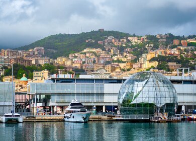 Der Alte Hafen (Porto Antico) in Genua, mit Yachten und Booten und dem größten Aquarium Europas im Vordergrund. Im Hintergrund sieht man die Stadt auf grünen Hügeln | © Gettyimmages.com/f9photos