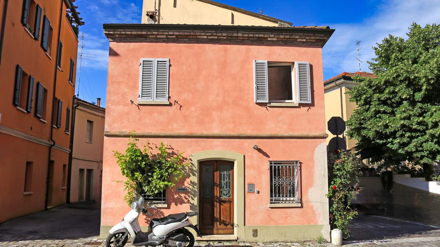 Charmantes kleines Haus im mediterranen Stil mit einem Motorroller in einer Gasse in Rimini, Italien | © Gettyimages.com/goce