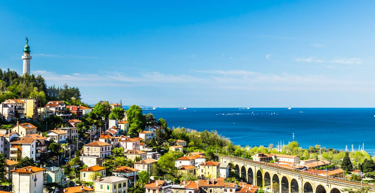 Panoramablick auf die Stadt Triest mit dem Faro della Vittoria, einer Brücke und dem Adriatischen Meer im Hintergrund | © Gettyimages.com/zakaz86