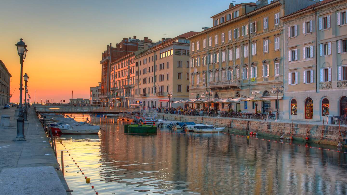 Atemberaubender Blick auf den Canal Grande und historische Gebäude in Triest während des Sonnenuntergangs | © Gettyimages.com/Bepsimage