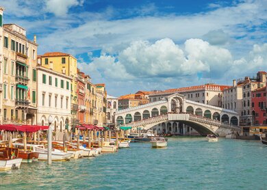 Im Hintergrund die Rialtobruecke mit Touristen, im Vordergrund anliegende Boote auf dem Canal Grande in Venedig. | © Gettyimages.com/mammuth