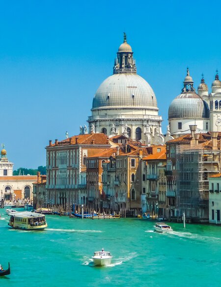 Gondeln fahren im Wasser auf dem Canal Grande in Venedig, die Basilica di Santa Maria della Salute im Hintergrund | © Gettyimages.com/bluejayphoto