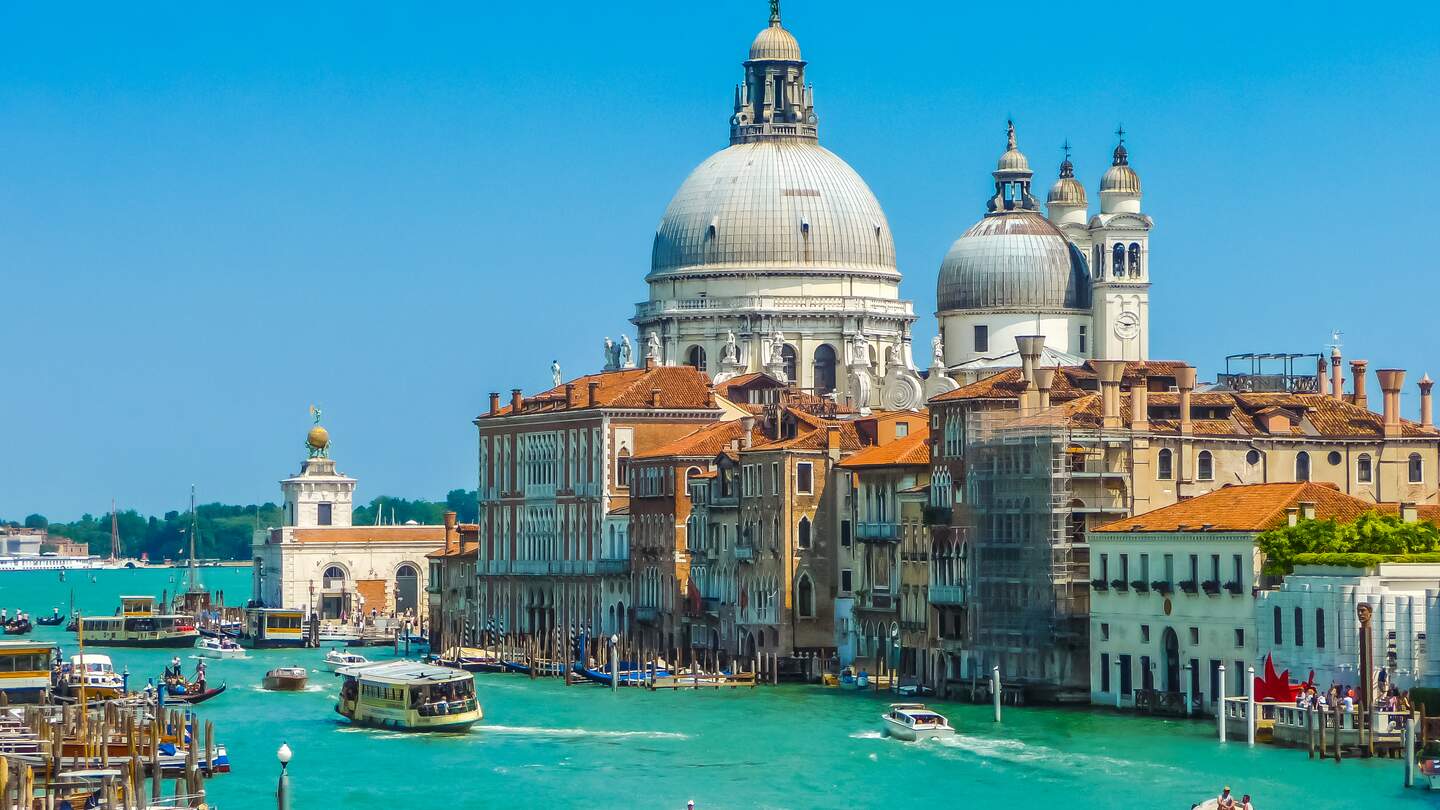 Gondeln fahren im Wasser auf dem Canal Grande in Venedig, die Basilica di Santa Maria della Salute im Hintergrund | © Gettyimages.com/bluejayphoto