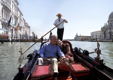 Glueckliches Paar, das an einem sonnigen Tag in einer Gondel auf dem Canal Grande sitzt. | © Gettyimages.com/Getty Images