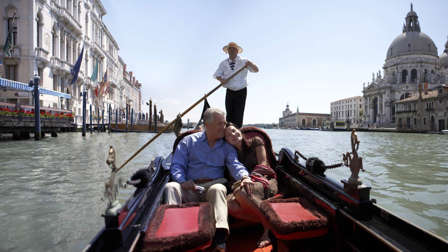 Glueckliches Paar, das an einem sonnigen Tag in einer Gondel auf dem Canal Grande sitzt. | © Gettyimages.com/Getty Images