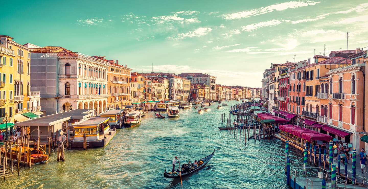 Ein Gondelfahrer paddelt in Richtung des Sonnenuntergangs auf dem grossen Kanal von Venedig. Aufnahme von der Rialto-Bruecke | © Gettyimages.com/JaCZhou