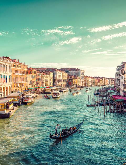 Ein Gondelfahrer paddelt in Richtung des Sonnenuntergangs auf dem grossen Kanal von Venedig. Aufnahme von der Rialto-Bruecke | © Gettyimages.com/JaCZhou