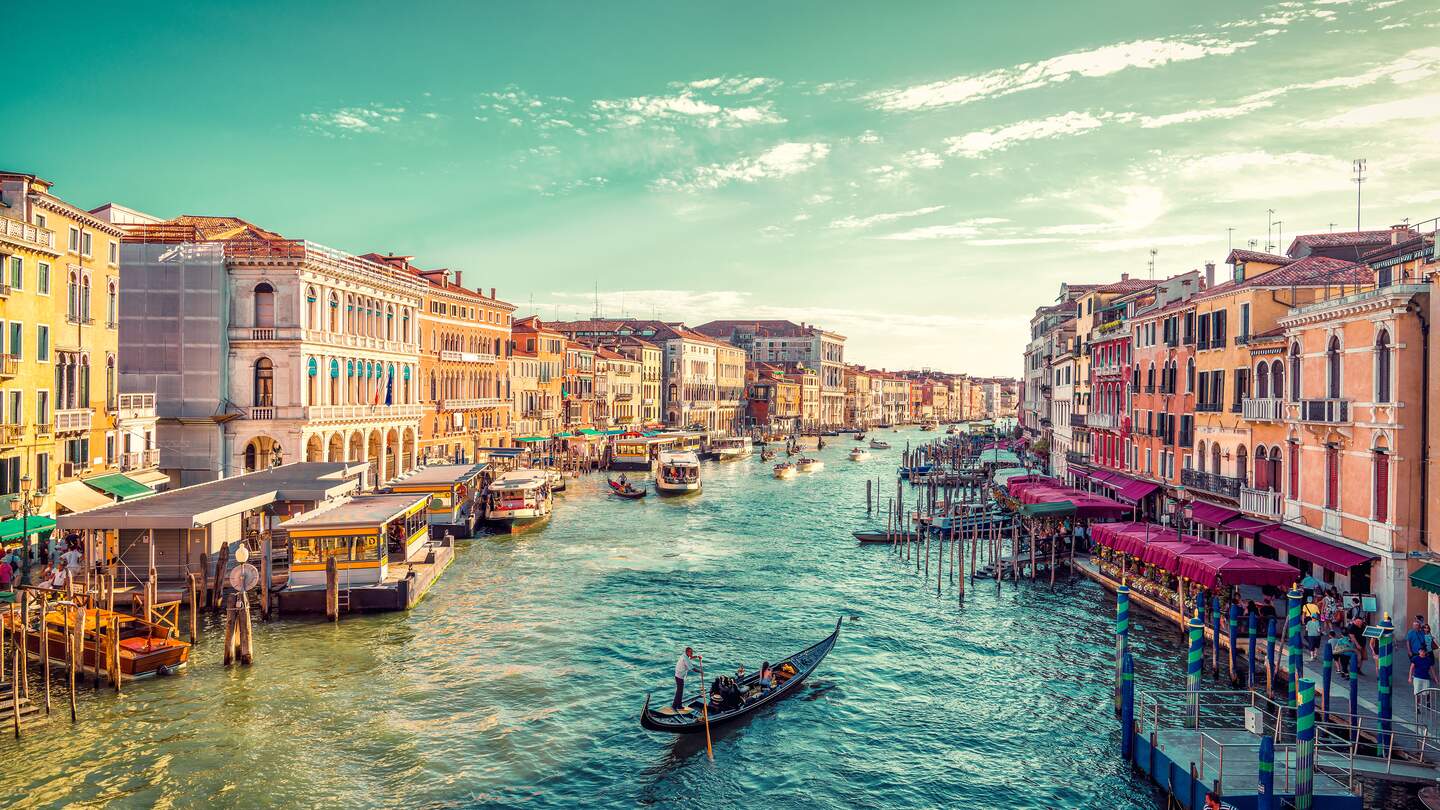 Ein Gondelfahrer paddelt in Richtung des Sonnenuntergangs auf dem grossen Kanal von Venedig. Aufnahme von der Rialto-Bruecke | © Gettyimages.com/JaCZhou