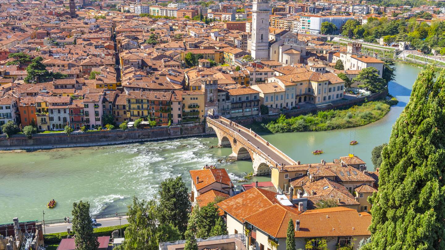 Blick auf das historische Zentrum der Stadt Verona, Italien und die Bruecke Ponte Pietra und die Etsch von der Huegelfestung Castel San Pietro, mit Gruppen von Floeßern, die eine Fahrt auf dem Fluss geniessen.  | © Gettyimages.com/kirkfisher