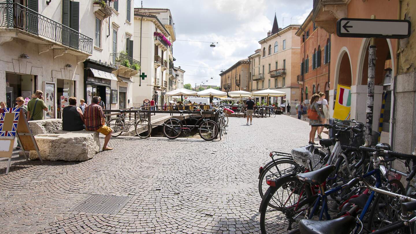 Strasse in Verona mit Touristen und Fahrraedern bei warmen Wetter | © GettyImages.com/RomanBabakin