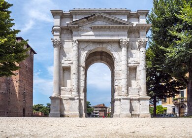 Frontale Untersicht auf den Arco dei Gavi in Verona bei hellblauem Himmel mit hellen Wolken | © GettyImages.com/pidjoe