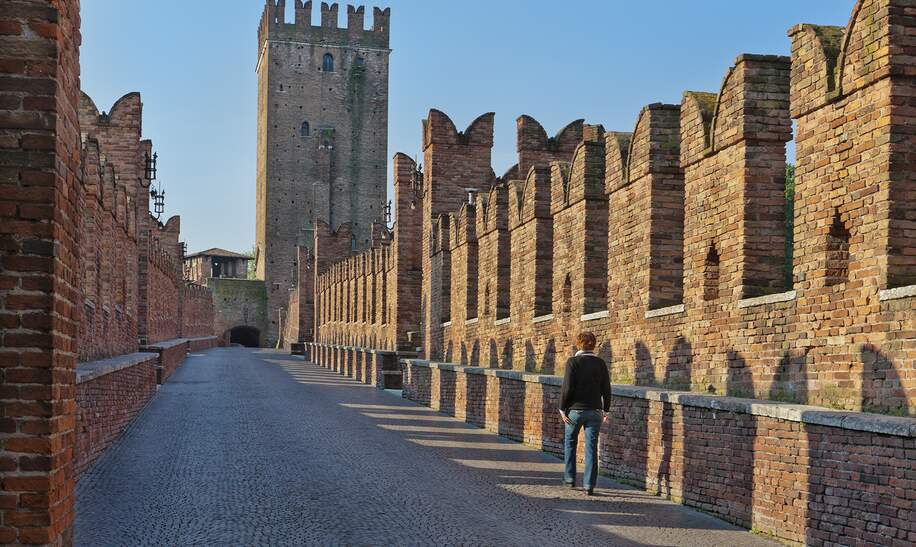 Frau auf der Castelvecchio-Bruecke ueber der Etsch mit roten Ziegeln in der oberen Seite und weissem Marmor in der unteren Seite | © GettyImages.com/Flavio Vallenari