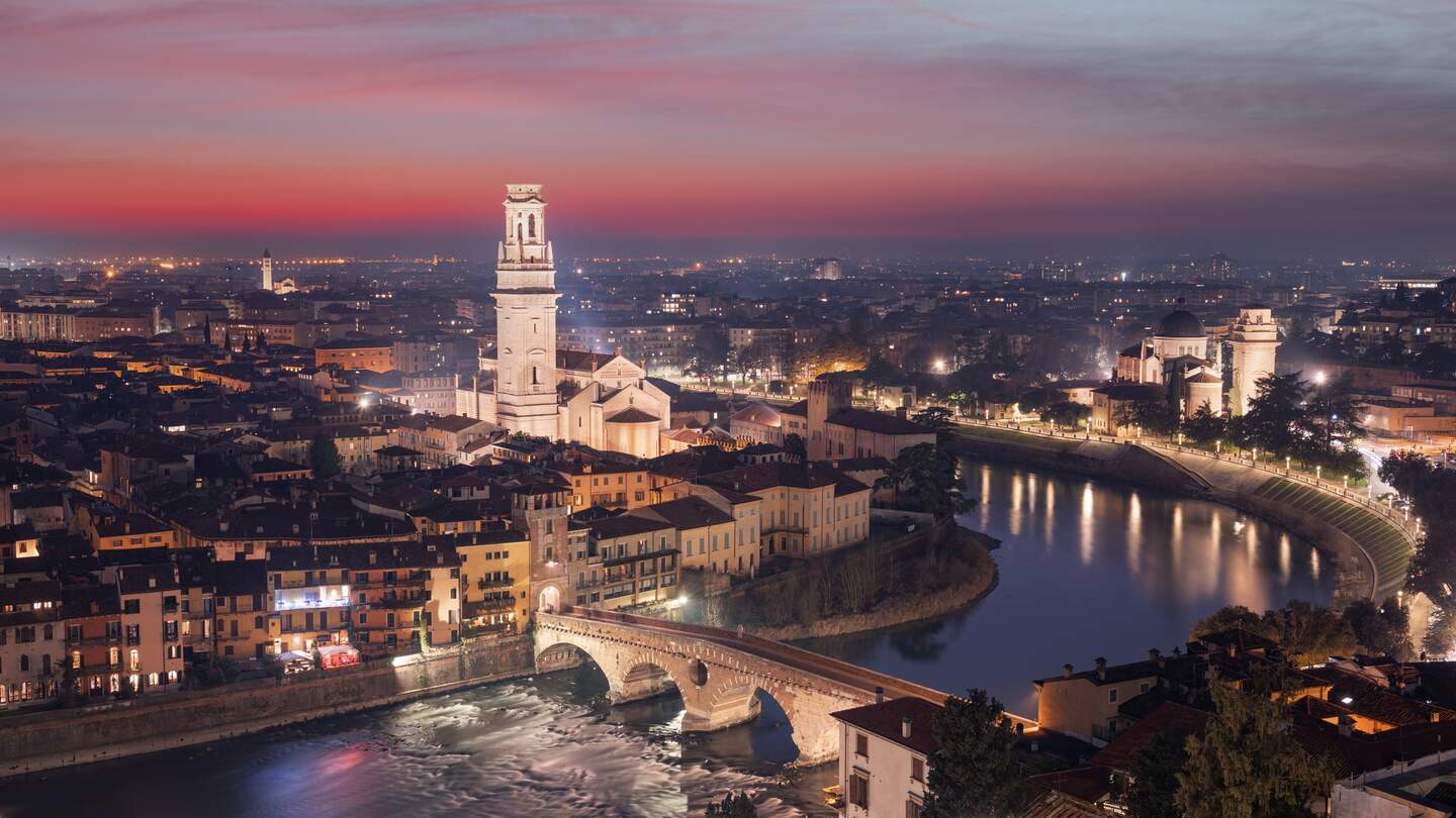 Beleuchtete Stadt Verona an der Etsch in der Abenddämmerung mit pinkem und lila Himmel | © Gettyimages.com/Sean Pavone