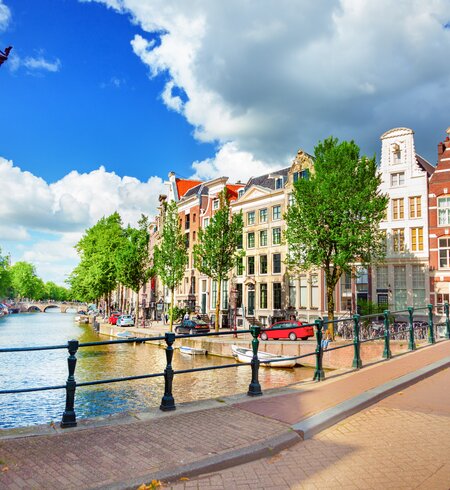 Blick auf die Amstel und eine Bruecke mit einer historischen Strassenlaterne im linken Vordergrund | © Gettyimages.com/adisa