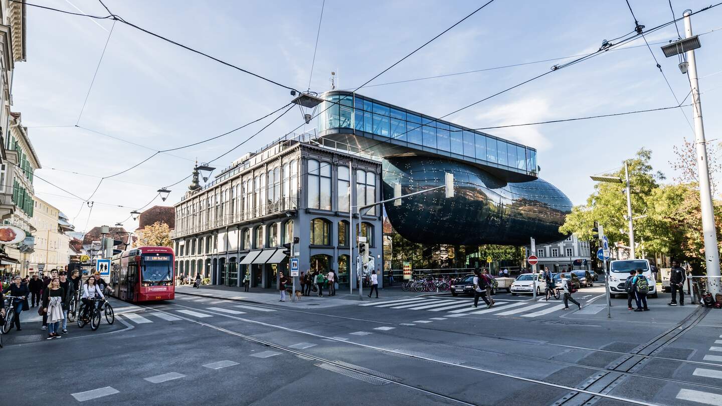 Menschen gehen vor dem Kunsthaus Graz, einem Ausstellungszentrum fuer zeitgenoessische Kunst. | © Gettyimages.com/breath10
