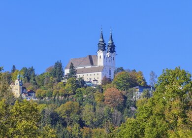 Blick auf die Basilika auf dem Poestlingberg  in Linz mit herbstlich gefaerbten Baeumen | © Gettyimages.com/Bertl123