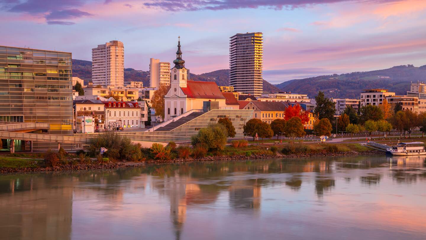 Stadtbild des Flussufers von Linz, Oesterreich bei wunderschoenem Herbstsonnenaufgang mit Spiegelung der Stadt in der Donau | © Gettyimages.com/RudyBalasko