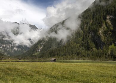 Ein kleiner See im Seebachtal, umgeben von den wolkenverhangenen Bergen der Hohen Tauern bei Mallnitz, Österreich.  | © Gettyimages.com/HannaGottschalk