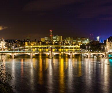 Das Rheinufer und die beleuchtete Stadt Basel bei Nacht | © Gettyimages.com/Leonid Andronov
