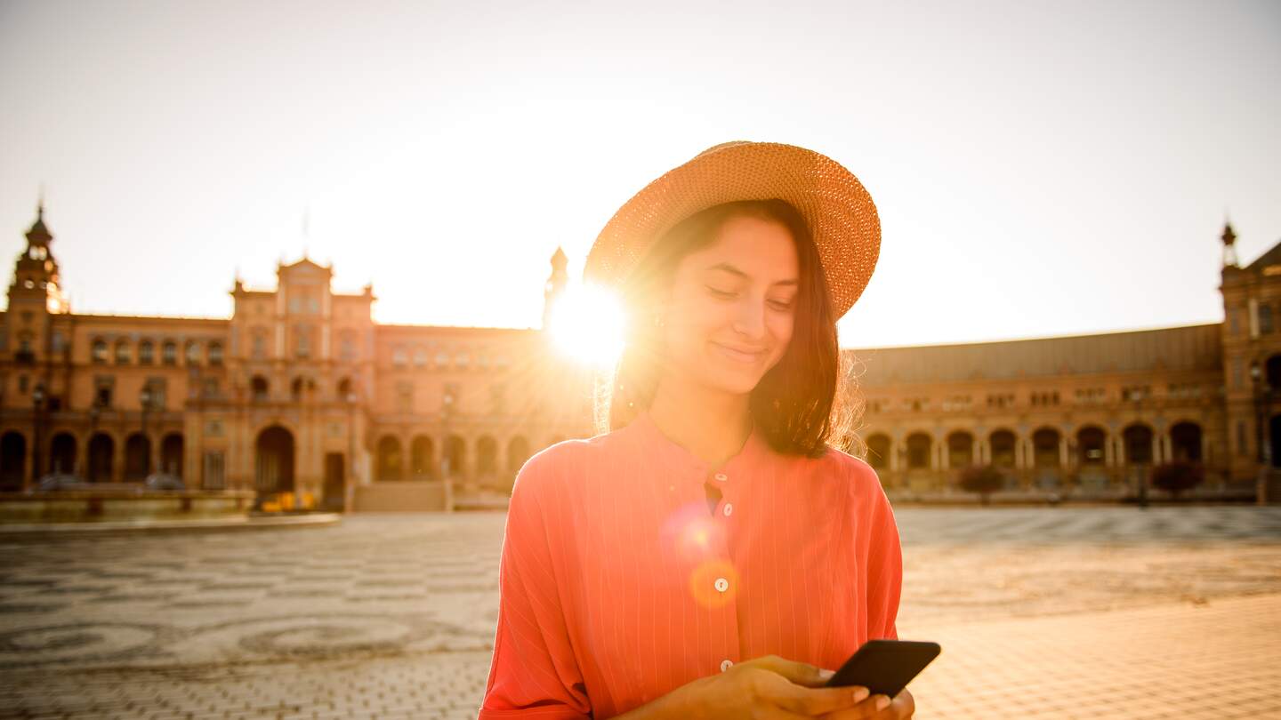 Elegante Frau beim Besuch der Plaza de Espana, Sevilla mit Handy in der Hand | © gettyimages.com/MStudioimages