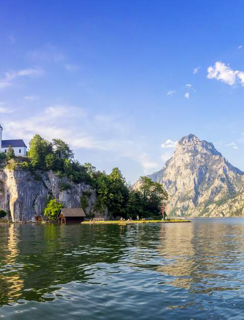 Im Vordergrund ist der See, doch im Zentrum steht die Kapelle auf dem Berg | © Gettyimages.com/dietermeyrl