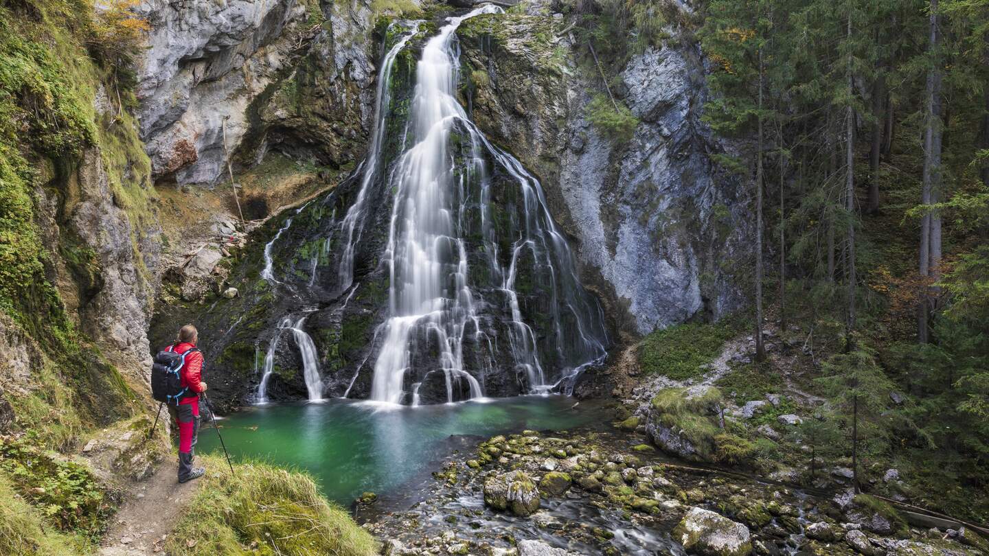 Maennliche Wanderer am idyllischen Wasserfall Szene mit bemoosten Felsen im Wald  | © Gettyimages.com/dietermeyrl