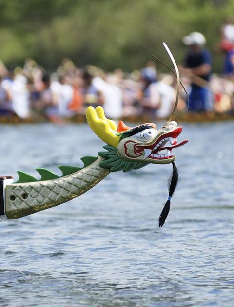 Bunt verzierter Bug eines Drachenbootes während eines Rennens auf einem See mit vielen Zuschauer  | © Gettyimages.com/EasyBuy4u