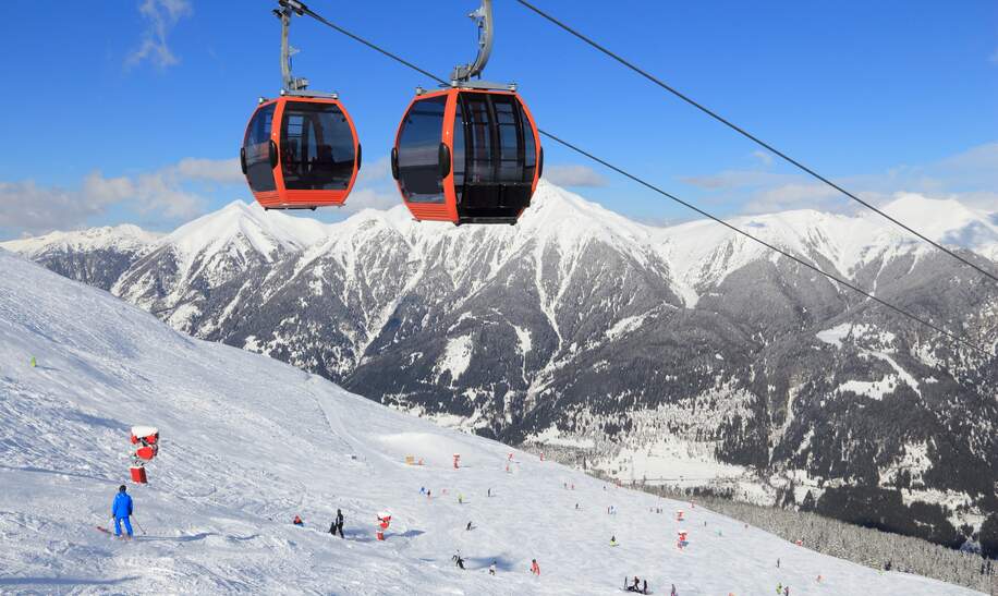 Skilift im Skigebiet Bad Gastein, umgeben von schneebedeckten Gipfeln der Hohen Tauern Alpen, unter klarem Winterhimmel. | © Gettyimages.com/tupungato