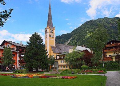 Die Kirche von Bad Hofgastein an einem sonnigen Sommertag mit Bergkulisse im Hintergrund | © Gettyimages.com/ABGlavin