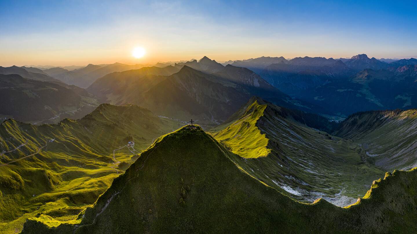 Luftaufnahme des Sonnenaufgangs auf dem Glatthorn (2133m) in Vorarlberg, dem westlichsten Teil Oesterreichs. Auf dem Gipfel des Berges liegen ein paar anonyme Menschen in ihren Schlafsaecken. | © Gettyimages.com/kemter