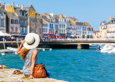Eine Frau sitzt am Ufer des Hafens in Le Corsic | © Gettyimages.com/margouillatphotos