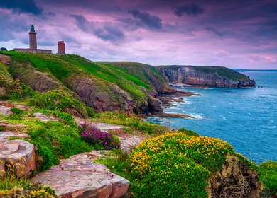 Wunderschöne felsige und blumige Küste mit Leuchtturm, Cap Frehel, Frankreich | © Gettyimages.com/janoka82