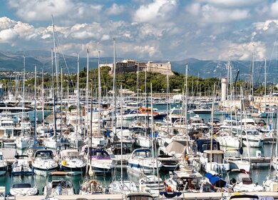 Blick auf den Seehafen. Festgemachte Boote und Yachten, Fort Carre im Hintergrund, viel Gruen  | © Gettyimages.com/starpik