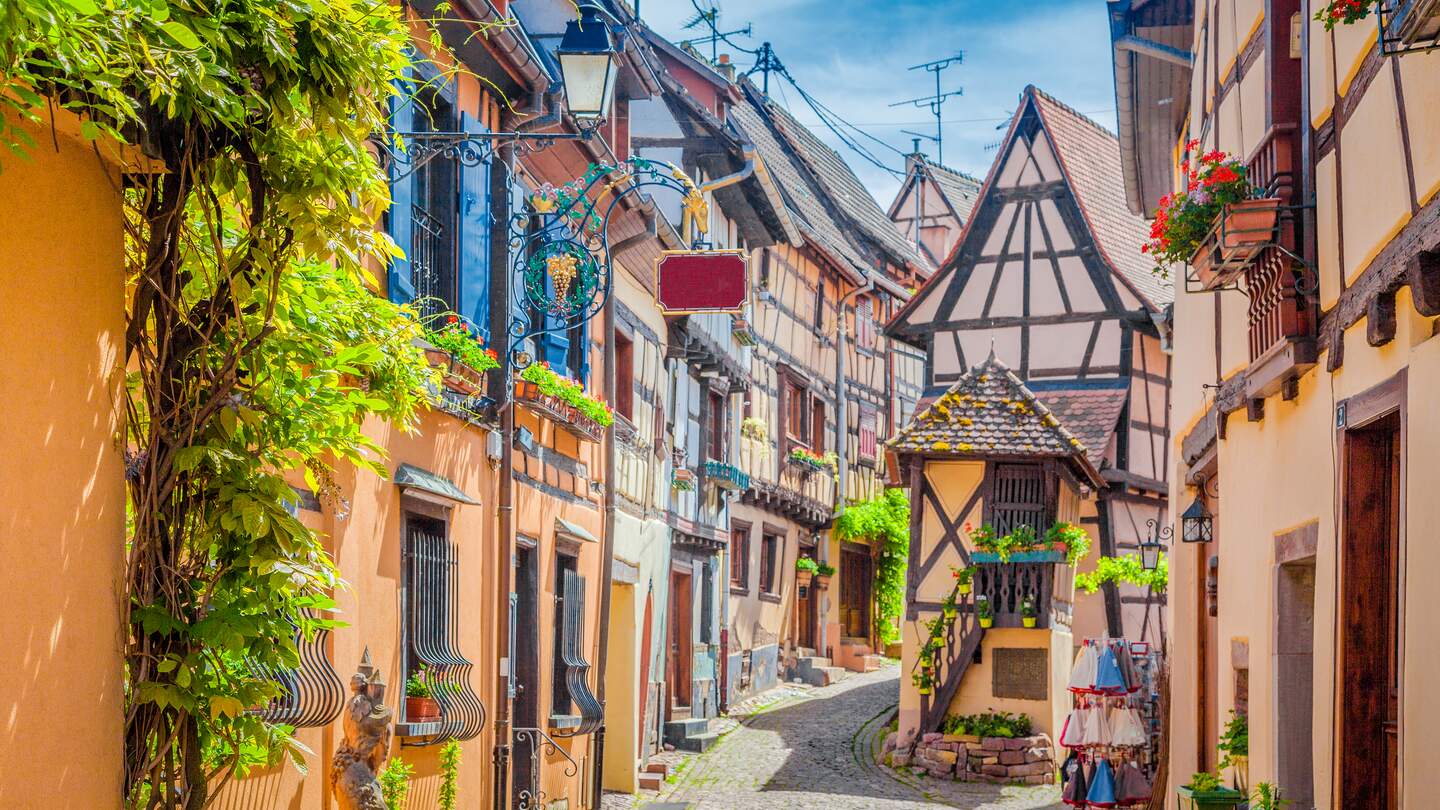 Charmantes Strassenbild mit bunten Haeusern in der historischen Stadt Eguisheim an einem schoenen sonnigen Tag mit blauem Himmel und Wolken im Sommer, Elsass | © Gettyimages.com/bluejayphoto