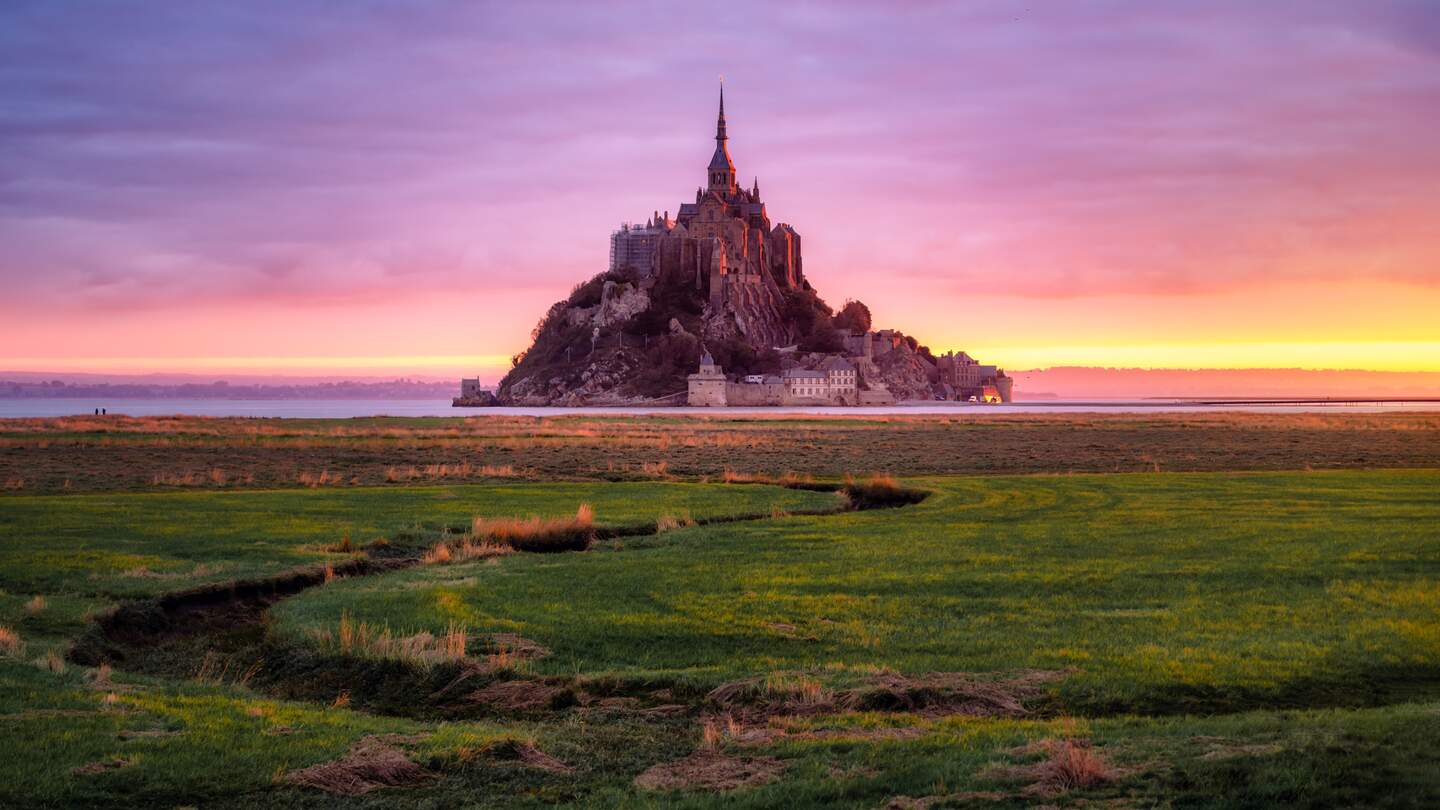 Blick auf den Mont Saint Michel bei Sonnenaufgang mit Ebbe und rosa Farben der Mäander. Normandie, Frankreich | © Gettyimages.com/eloi_omella