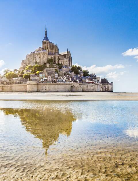 Panoramablick auf die beruehmte Gezeiteninsel Le Mont Saint-Michel an einem sonnigen Tag mit blauem Himmel und Wolken, Normandie, Nordfrankreich | © Gettyimages.com/bluejayphoto