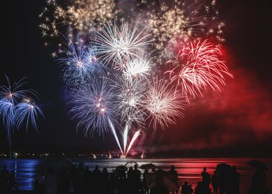 Schoene blaue, weisse und rote Feuerwerk Pyrotechnik wie, franzoesische Flagge Farben mit unkenntlich Menge Silhouetten beobachten | © Gettyimages.com/gregory_dubus