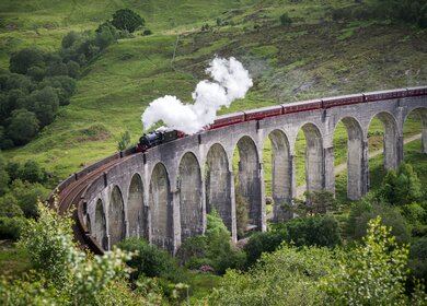 Dampfzug faehrt ueber das Glenfinnan-Viadukt in Schottland | © Gettyimages.com/wanderluster