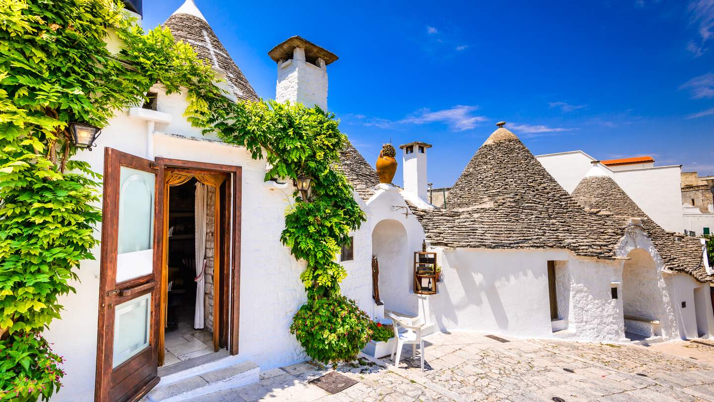 Typische weiss getuenchte Trulli-Haeuser mit ihren kegelfoermigen Daechern der Stadt Alberobello | © Gettyimages.com/emicristea